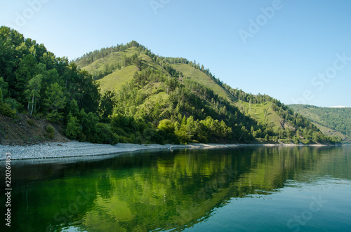 Landscape of the shore of the lake with rocks and mountains in the background