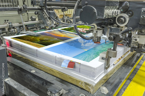 offset machine press print run at table, sheetfed paper feeder unit. Poster printing photo