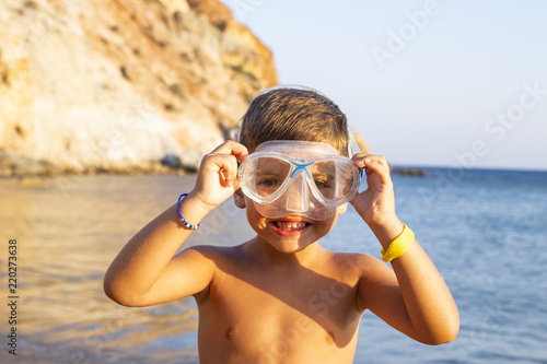 Kid with diving goggles on the shore of the ocean