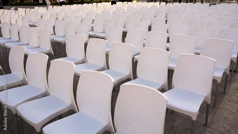 Naklejka premium Many white chairs. Rows of plastic white chairs - seats for spectators or fans.