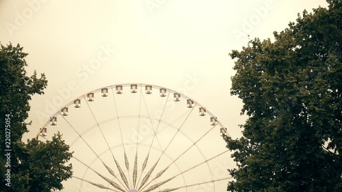 Ferris-wheel in Paris from Tuileries Gardens and Louvre museum at sunset photo