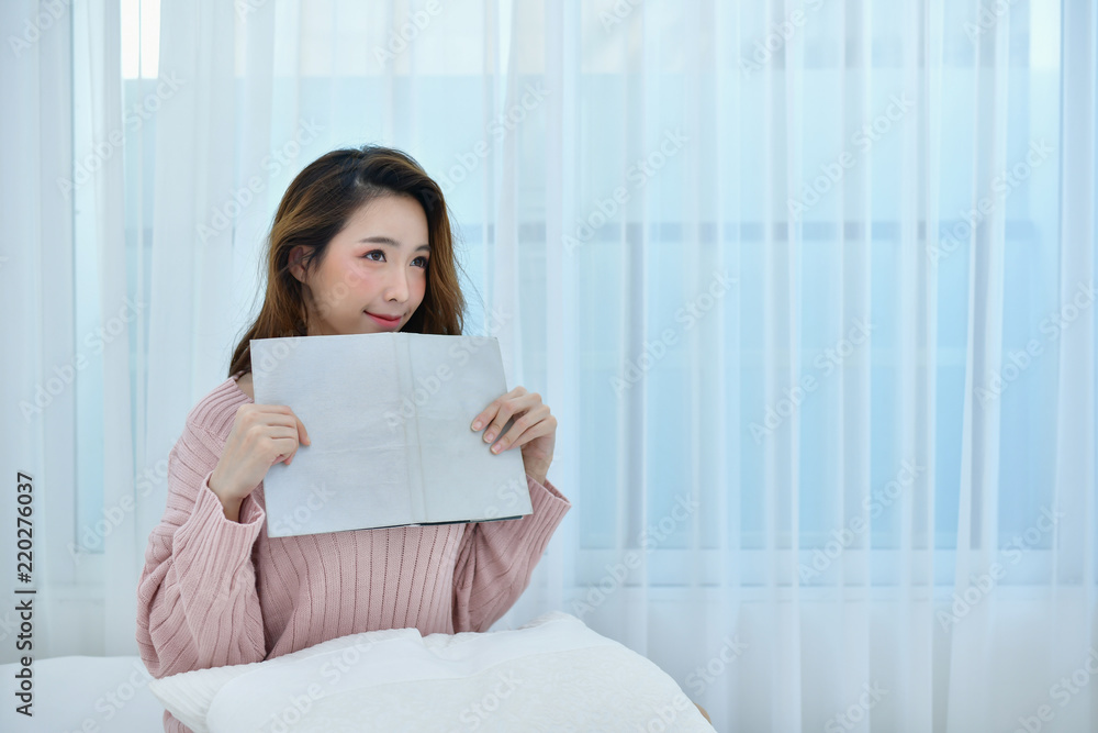 education Winter Concept. Cute Asian girl in winter dress. Beautiful woman is relaxing in a white bedroom. Beautiful women in winter wear are studying in the bedroom. Woman wearing sweater in bedroom. education Winter Concept. Cute Asian girl in winter dress. Beautiful woman is relaxing in a white bedroom. Beautiful women in winter wear are studying in the bedroom. Woman wearing sweater in bedroom.