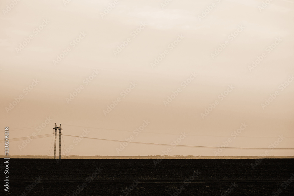 Power lines on background of sky close-up. Silhouette of electric pole with copy space in sepia tones. Wires of high voltage above ground. Electricity industry in monochrome.