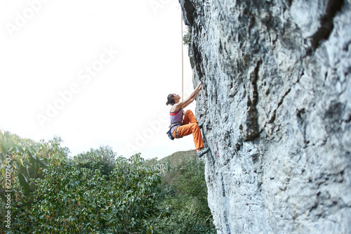 young slim woman rock climber climbing on the cliff