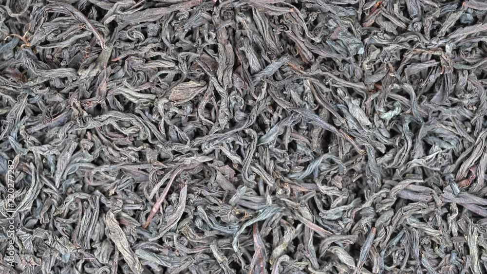 Large leaves of black tea background, close up. Loop rotation. Front of the camera rotates plate with black tea, macro Large leaves of black tea background, close up. Loop rotation. Front of the camera rotates plate with black tea, macro