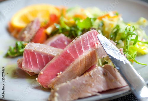 Fish tuna meat dish on plate with orange and vegetables. Food of modern mediterranian restaurant.