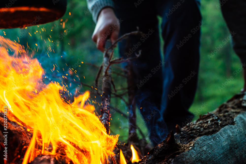 Man kindles bonfire in forest. Atmospheric flame of campfire close up. Camping on nature. Active rest. Recreation open air. Beautiful orange fire with smoke with copy space. Man kindles bonfire in forest. Atmospheric flame of campfire close up. Camping on nature. Active rest. Recreation open air. Beautiful orange fire with smoke with copy space.