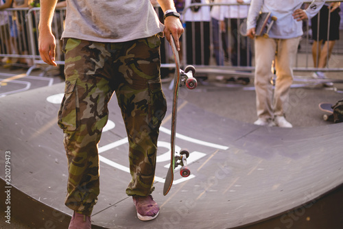 young rider holding a skateboard on competition tournament