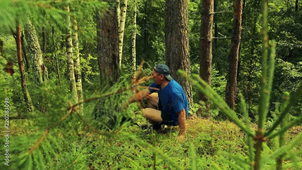 A tourist man takes off his backpack and sits down to rest and admire nature. A tourist man takes off his backpack and sits down to rest and admire nature.