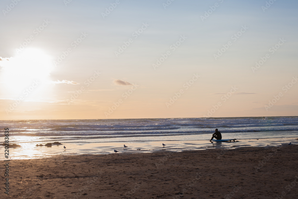 Surfer on the ocean beach at sunset