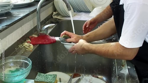 Man washing dishes in restaurant kitchen, slow motion photo