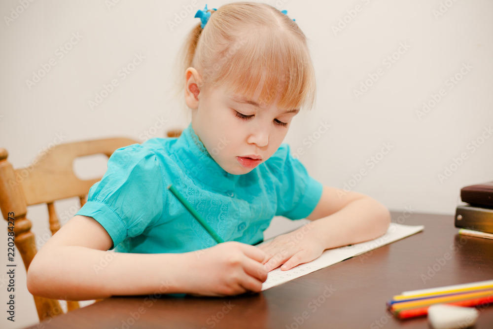 Cute little girl writing her homework at the table Cute little girl writing her homework at the table