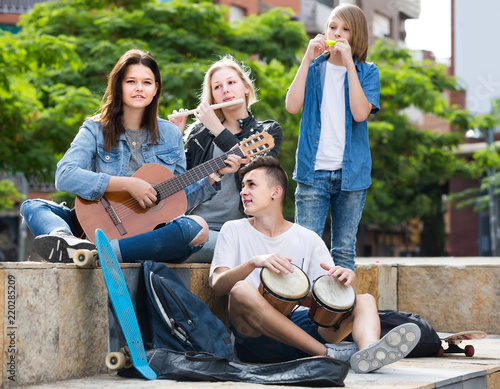 Portrait of four teenagers playing music together outdoors © JackF