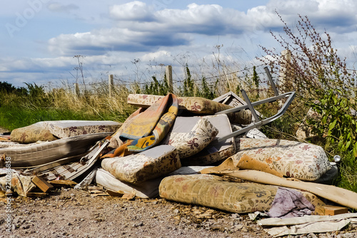 Blight of illegally dumped household rubbish left in a little used country lane. Environmental hazard, with furniture. mattresses and carpets. Fly tipped detritus. Oxfordshire.