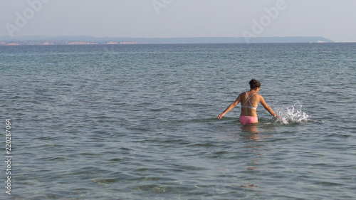 Lonely young woman plays alone in sea shallow water splashing with her hands © zefart