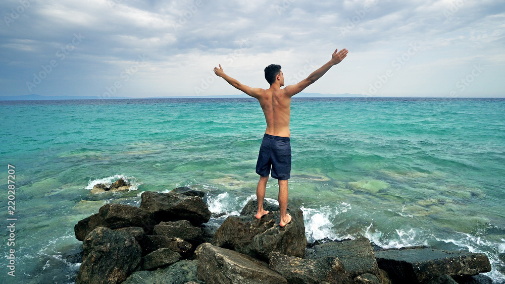 Teen Male makes a beach speech with hands open to sea, freedom concept