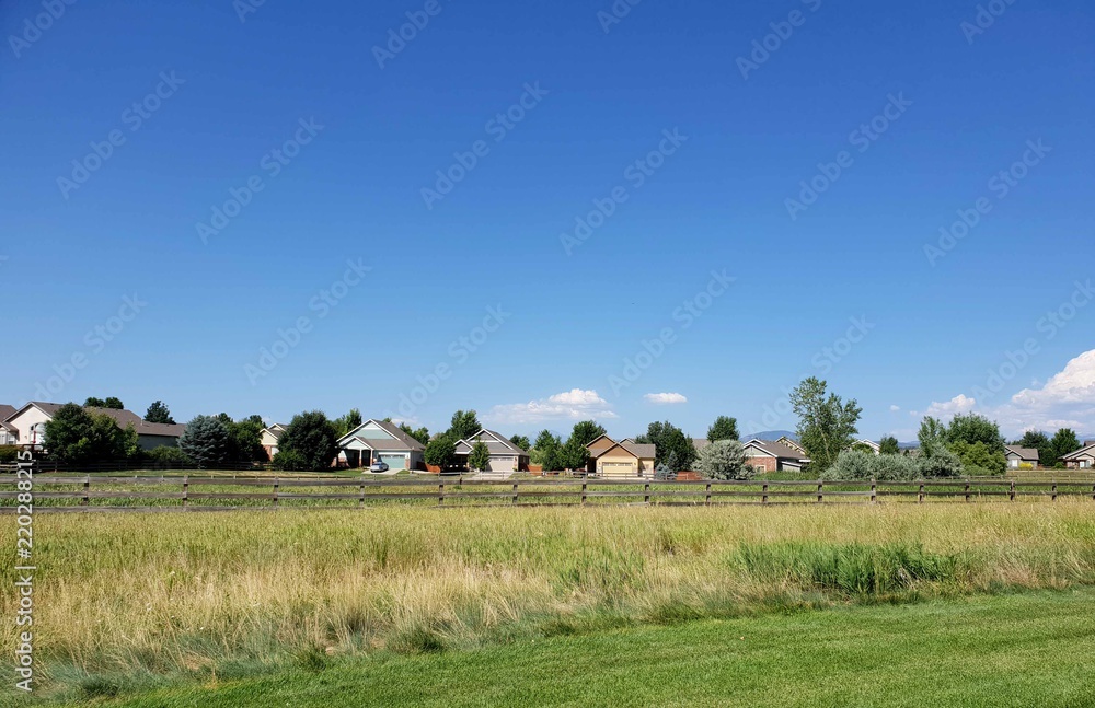 Fototapeta premium Field with a Fence and Houses
