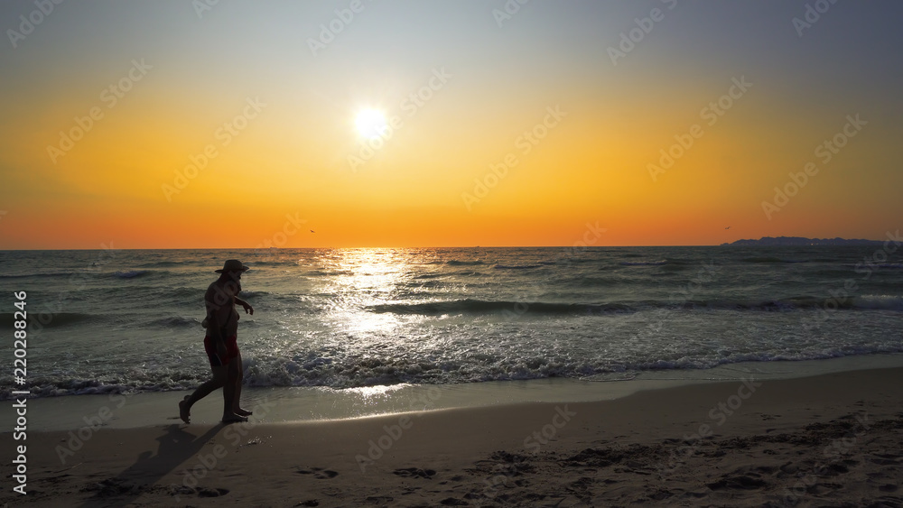 Loving Couple Holding Hands Beach Vacation Sunset - Young ethnic couple holding hands watching sunset on beach vacation