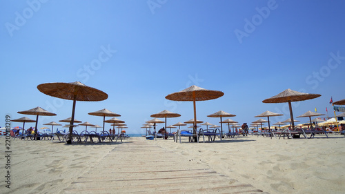 Empty Sunny Beach with Umbrellas  Sun Beds on the Ionian Sea. The coastal resort line  where people relax and sunbathe