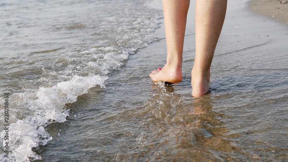 Following a barefoot female feet walking and splashing on sea water waves, cinematic steadicam shot Following a barefoot female feet walking and splashing on sea water waves, cinematic steadicam shot