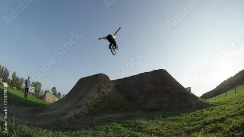 Extreme sports athlete doing tricks in slow motion on a big BMX dirt jump with his bicycle photo