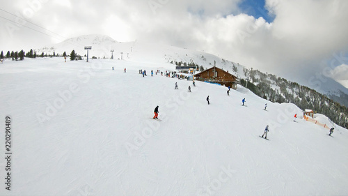 Aerial view from ski lift to ski piste with strong wind and snow drifting at the top of mountain summit, slow motion