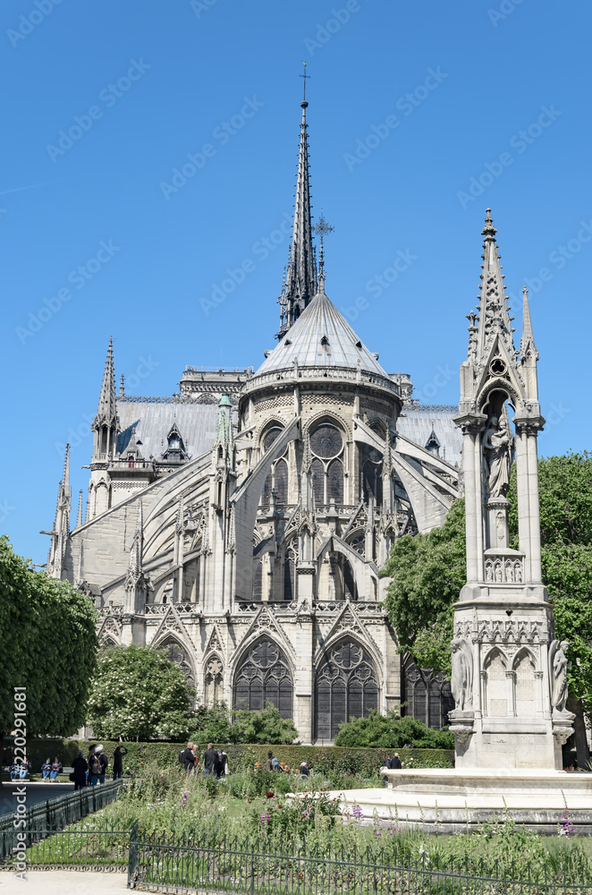 View of the East-end of the Notre-Dame de Paris cathedral in the morning with the fountain of the Virgin in the foreground, vertical