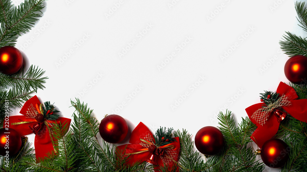 View from above on Christmas and New Year background with green branches of fir tree red glass balls and red bows bells on white background. Copy space. Horizontal. View from above on Christmas and New Year background with green branches of fir tree red glass balls and red bows bells on white background. Copy space. Horizontal.
