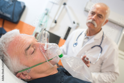senior man using oxygen mask in clinic