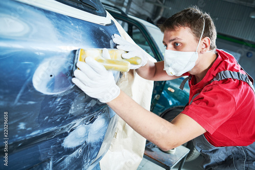 auto repairman grinding automobile body