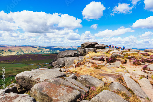 Walking in Peak District National Park, Derbyshire, England. Stacked rock formations in Stanage edge, with the fields and pastures on the background, selective focus