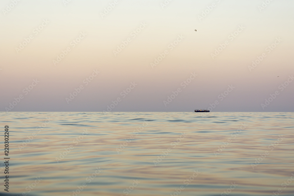evening sea with waves, far away on a horizon line floating ship, nature abstract background