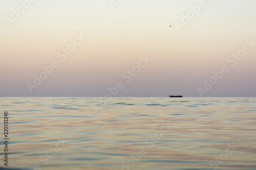 evening sea with waves  far away on a horizon line floating ship  nature abstract background