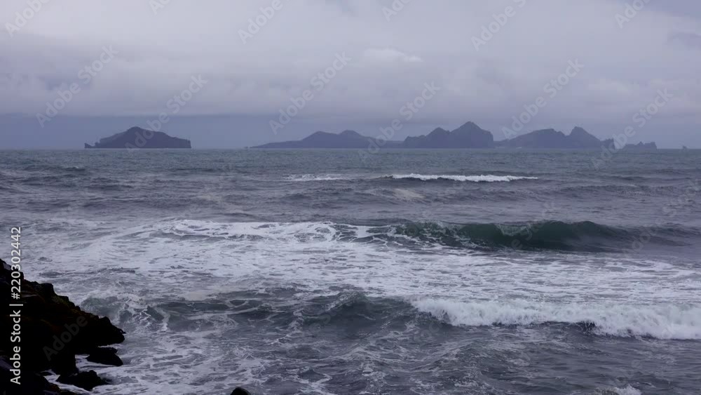 Establishing shot of the Westmann Islands in Iceland with a stormy dark sea foreground. Establishing shot of the Westmann Islands in Iceland with a stormy dark sea foreground.