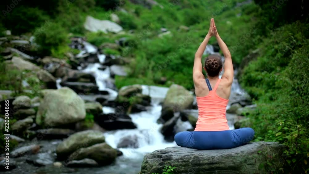 Woman meditating at tropical waterfall Woman meditating at tropical waterfall