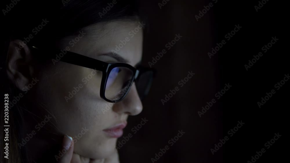 A young girl in glasses works for a laptop outside of working hours. Girl In A Dark Room, Surf The Internet Using A Laptop, Extreme Close-Up Eye A young girl in glasses works for a laptop outside of working hours. Girl In A Dark Room, Surf The Internet Using A Laptop, Extreme Close-Up Eye