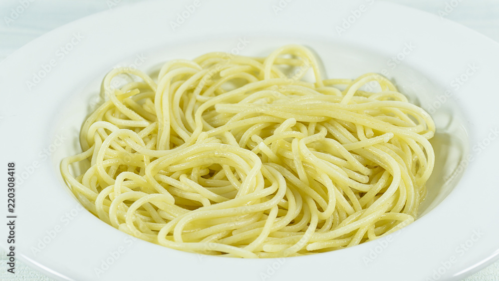 Spaghetti yellow italian pasta line in a white dish on a table, Close up with copy space for your text. Spaghetti yellow italian pasta line in a white dish on a table, Close up with copy space for your text.