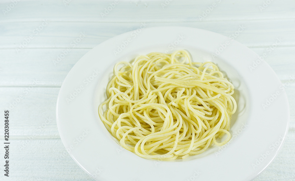 Spaghetti yellow italian pasta line in a dish on a white wood floor table, Front view with copy space for your text.. Spaghetti yellow italian pasta line in a dish on a white wood floor table, Front view with copy space for your text..