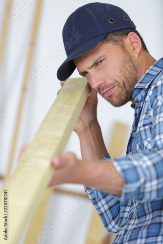 handsome carpenter measuring wood