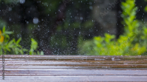 drops of rain fall on a wooden terrace and a bridge near the pool