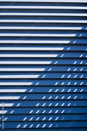 A blue wall the sun dives over , Metal striped wall, special blue wall, light blue wall, shades of sun, steps wall, designed wall, wall background, light blue background
