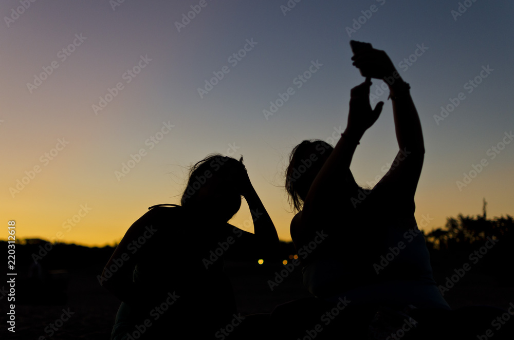 silhouette of two people taking a picture at dusk