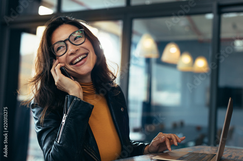 Fotografie Smiling business woman in casuals talking on phone