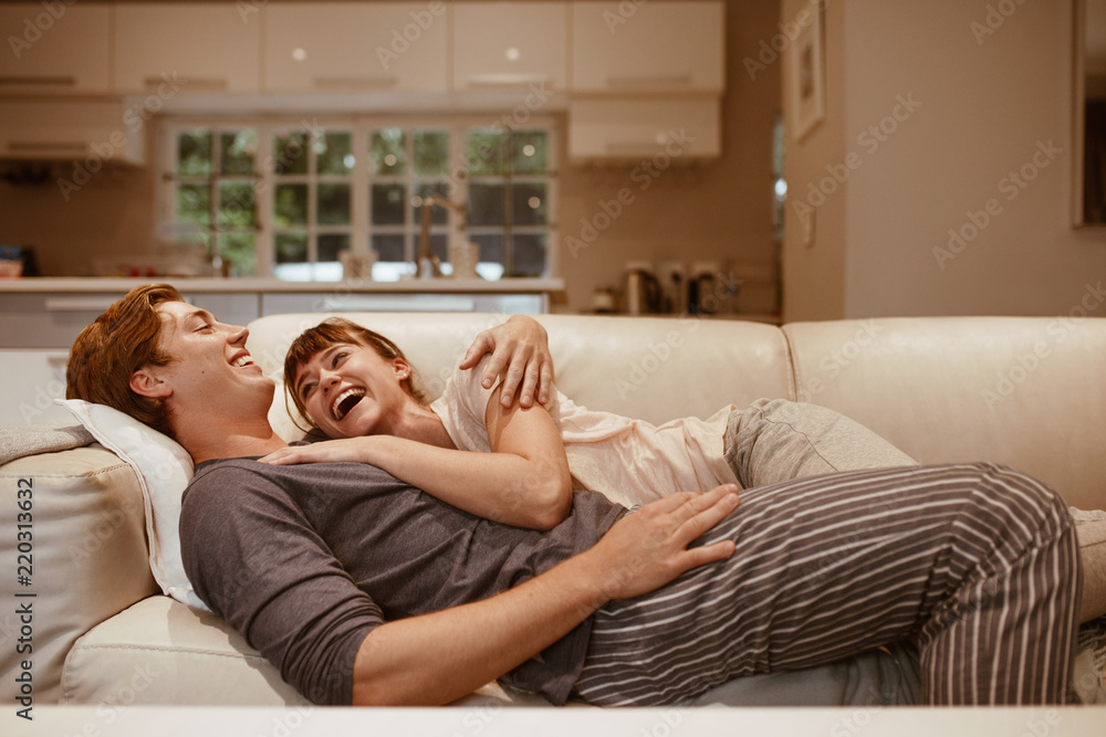 Smiling couple lying on a couch together Smiling couple lying on a couch together
