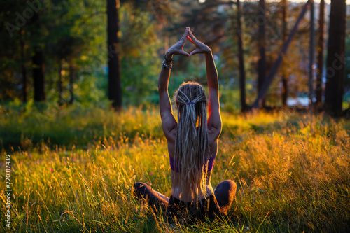 Yoga woman on a picturesque glade in a green forest.