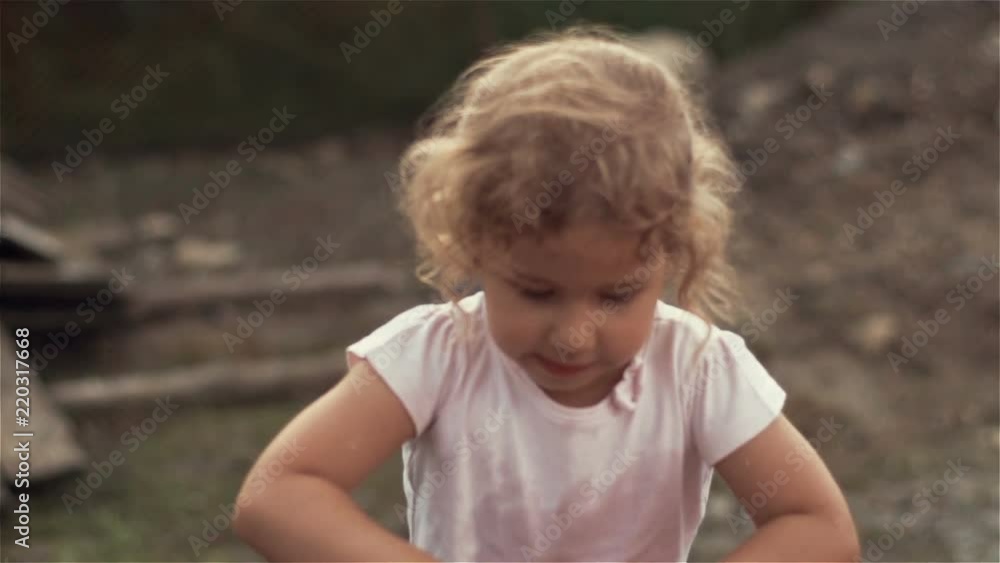 A beautiful little blonde girl with curly hair splashing water into the camera and smiles. Slow motion at 100fps A beautiful little blonde girl with curly hair splashing water into the camera and smiles. Slow motion at 100fps