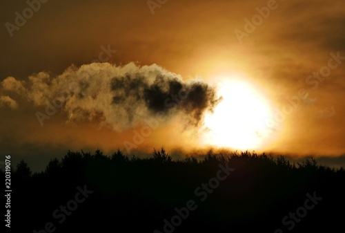 beautiful dramatic sunset with clouds over treeline silhouette