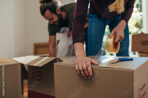 Close up of a woman applying adhesive tape on a packing box photo