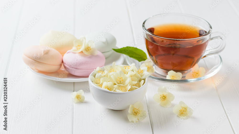 Herbal tea, a bowl of marshmallows and jasmine flowers on a table. The composition of the morning Breakfast. Herbal tea, a bowl of marshmallows and jasmine flowers on a table. The composition of the morning Breakfast.
