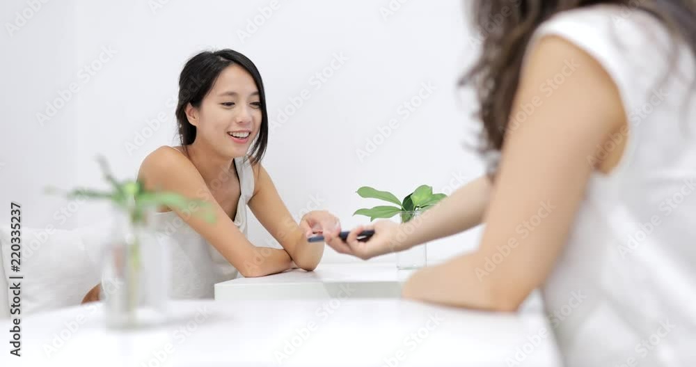 Women friends talk in coffee shop and looking at mobile phone together Women friends talk in coffee shop and looking at mobile phone together